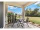 Charming screened patio features a cozy table setting, perfect for enjoying outdoor meals with serene views of the well-manicured backyard at 412 Daylily Blvd, Nokomis, FL 34275