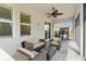 Inviting covered patio with comfortable seating, ceiling fan, and a charming view of the landscaped backyard and neighborhood at 412 Daylily Blvd, Nokomis, FL 34275