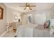 Well-lit bedroom features a ceiling fan, white furnishings, and a view into the ensuite bathroom at 5230 Landings Blvd # 101, Sarasota, FL 34231