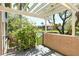 Charming outdoor patio area with pergola, blossoming plants, and tranquil water view at desirable community at 5230 Landings Blvd # 101, Sarasota, FL 34231