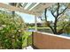 Charming outdoor patio area with pergola, blossoming plants, and tranquil water view at desirable community at 5230 Landings Blvd # 101, Sarasota, FL 34231