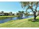 Scenic water view featuring a lush green lawn, mature shade trees, and a tranquil fountain at 5230 Landings Blvd # 101, Sarasota, FL 34231