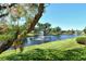 Scenic water view featuring a lush green lawn, mature shade trees, and a tranquil fountain at 5230 Landings Blvd # 101, Sarasota, FL 34231