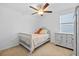 Bright bedroom featuring carpet flooring, a ceiling fan, a window, and a light gray bed with a dresser at 5554 Blue Azure Dr, Wimauma, FL 33598