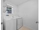 Bright laundry room with white washer and dryer, wire rack and window at 5554 Blue Azure Dr, Wimauma, FL 33598