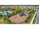 Overhead shot of a neighborhood playground with slides and swings, surrounded by trees and landscaping at 5554 Blue Azure Dr, Wimauma, FL 33598