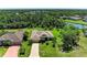 Aerial shot of a single-story house with a long driveway, surrounded by mature trees, lush greenery and a waterway at 5616 90Th Avenue E Cir, Parrish, FL 34219