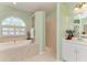 Bright primary bathroom featuring a soaking tub under an arched window and a tiled walk-in shower at 5616 90Th Avenue E Cir, Parrish, FL 34219
