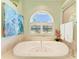 The primary bathroom showcases a large soaking tub under an arched window, creating a spa-like retreat at 5616 90Th Avenue E Cir, Parrish, FL 34219