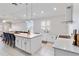 Open-concept kitchen with white cabinets, stainless steel appliances, island with seating, and a view to the living area at 5919 100Th E Ave, Parrish, FL 34219