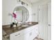 Bright bathroom featuring white cabinetry, a vessel sink, and a round mirror with decorative lighting at 750 N Tamiami Trl # 1203, Sarasota, FL 34236