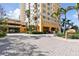 Elegant building entrance with guest parking and a well-manicured landscape featuring mature palm trees at 750 N Tamiami Trl # 1203, Sarasota, FL 34236