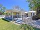 Yellow home featuring a covered patio, white gravel, a metal roof, and a lush green lawn at 763 Siesta Dr, Sarasota, FL 34242