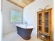 Bathroom featuring a soaking tub, wood cabinet, and window at 763 Siesta Dr, Sarasota, FL 34242
