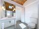 Bathroom features a pedestal sink, toilet, wood ceiling, shiplap walls, and an open shower at 763 Siesta Dr, Sarasota, FL 34242