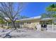 Quaint yellow home featuring a light-colored metal roof, brick-paved driveway, and well-manicured landscaping at 763 Siesta Dr, Sarasota, FL 34242