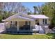 Charming yellow home with a metal roof, covered porch, gray railings, and a lush green lawn at 763 Siesta Dr, Sarasota, FL 34242