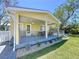Charming covered porch featuring outdoor seating, complemented by lush green lawn and landscaping at 763 Siesta Dr, Sarasota, FL 34242