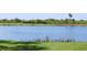 Peaceful pond surrounded by green grass and trees with golf carts visible in the background on a sunny day at 7803 Grand Estuary Trl # 205, Bradenton, FL 34212