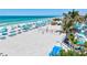 Beautiful beachfront with white sand, blue umbrellas, and palm trees create a serene vacation atmosphere at 845 Benjamin Franklin Dr # 106, Sarasota, FL 34236