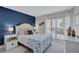 Bright bedroom with nautical decor, blue accent wall, and view to outdoors through shuttered window at 845 Benjamin Franklin Dr # 106, Sarasota, FL 34236