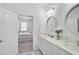 Modern bathroom showcasing a double vanity with round mirrors, and neutral tones with a bedroom view, creating a spa-like retreat at 8553 Whispering St, Sarasota, FL 34240