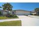 Well-maintained home exterior with a paved driveway, lush lawn, and tropical landscaping at 8553 Whispering St, Sarasota, FL 34240