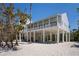 Elegant beach house on stilts showcases a spacious wraparound porch with decorative railings at 9265 Blind Pass Rd, Sarasota, FL 34242