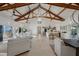 Expansive living area boasts exposed beams and a modern kitchen with stainless steel appliances and tile flooring at 9265 Blind Pass Rd, Sarasota, FL 34242