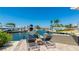 Waterfront view of a house with a boat lift and waterfront patio with chaise lounges and outdoor seating area at 10008 Spoonbill E Rd, Bradenton, FL 34209
