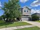 Charming two-story gray home featuring a stone facade and manicured lawn with mature trees at 10934 79Th E St, Parrish, FL 34219