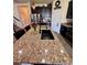 Spacious kitchen island featuring granite countertops, a black sink, bar seating and dark cabinetry at 10934 79Th E St, Parrish, FL 34219