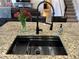 Close-up of a kitchen island featuring a black sink, granite countertop, and modern faucet at 10934 79Th E St, Parrish, FL 34219