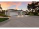 Charming single-story home featuring a large driveway and a two-car garage, beautifully enhanced by a colorful sunset at 1411 70Th Nw St, Bradenton, FL 34209