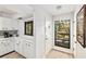 Bright kitchen entrance with white cabinets, view of lush greenery, and a convenient front door at 1711 Pelican Cove Rd # 443, Sarasota, FL 34231