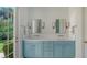 Light and airy bathroom features a double vanity, quartz countertop, blue cabinets, and French doors to the backyard at 228 Saint James Park, Osprey, FL 34229