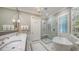Bright bathroom features a marble shower, soaking tub, double vanity with marble countertop and stylish fixtures at 228 Saint James Park, Osprey, FL 34229