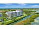 Aerial view featuring a condo building next to waterways, golf courses, and a marina at 2450 Harbourside Dr # 233, Longboat Key, FL 34228
