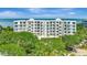 Exterior view of building with lush landscaping and views of water in the distance at 2450 Harbourside Dr # 233, Longboat Key, FL 34228