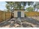 Exterior shot of the shed in the backyard with wood fencing, a gravel base, and surrounded by beautiful trees at 2848 Trinidad St, Sarasota, FL 34231
