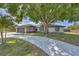 Charming home featuring a stone-accented facade, attached garage, and a spacious, curved driveway, all shaded by a mature tree at 3136 Webber St, Sarasota, FL 34239