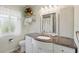 Bathroom has a white vanity with dark countertop, decorative mirror, window, and white shower curtain at 3260 Pinetree St, Port Charlotte, FL 33952