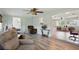 Living room boasts wood floors, a ceiling fan, and two brown cushioned chairs with views to other rooms at 3260 Pinetree St, Port Charlotte, FL 33952