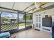 Enclosed sunroom with wood flooring and a ceiling fan looks out onto the backyard at 3260 Pinetree St, Port Charlotte, FL 33952