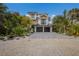 Charming two-story home boasts a two-car garage, balcony, stone driveway, and mature tropical landscaping at 408 Magnolia Ave, Anna Maria, FL 34216
