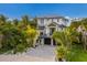 Stunning two-story white home with black trim, lush tropical landscaping and a paved driveway at 408 Magnolia Ave, Anna Maria, FL 34216
