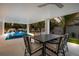 Covered outdoor patio with dining table and chairs overlooking the pool and hot tub at 408 Magnolia Ave, Anna Maria, FL 34216