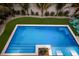 Aerial view of the sparkling blue pool with meticulous landscaping, lush green lawn, and stylish Adirondack seating at 408 Magnolia Ave, Anna Maria, FL 34216