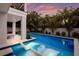 Relax in the pool on the stylish white lounge chairs with beautiful views of the home and tropical landscaping at 408 Magnolia Ave, Anna Maria, FL 34216