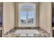 Bright bathroom featuring a soaking tub with granite surround and shuttered window at 416 Casey Key Rd, Nokomis, FL 34275